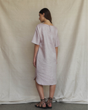 Woman wearing a light pink dress standing against a plain background