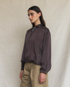 Model wearing a dark brown silk aviator bomber jacket.