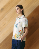 Model wearing a colourful, patchwork polo shirt against a wooden wall.
