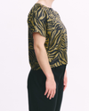 Person wearing a black and gold zebra print top with black pants on a white background