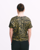 Person wearing a black and gold zebra print top with black pants on a white background