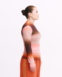 Woman wearing a long-sleeve top with a gradient design on a white background