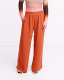 Orange wide-leg pants worn by a person on a white background