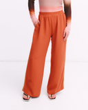 Orange wide-leg pants worn by a person on a white background