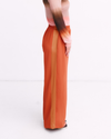 Orange wide-leg pants worn by a person on a white background