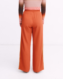 Orange wide-leg pants worn by a person on a white background