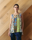 Model wearing a colorful patterned top against a wooden wall.