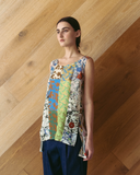 Woman wearing a colorful patterned top against a wooden wall.