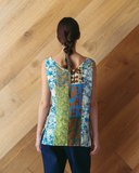 Person wearing a colorful sleeveless top with a wooden floor background