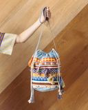 Colourful drawstring bucket bag with patterns against a wooden wall