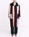 Person wearing a long, multicolored coat with a white background