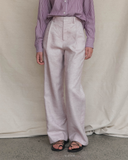 Model wearing a striped shirt and light-pink coloured pants against a plain background