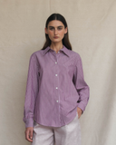 Woman wearing a plum striped shirt against a beige background
