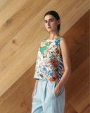 Model wears spliced patchwork top against wooden background