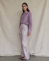 Model wearing a purple striped shirt and light coloured pants against a plain background