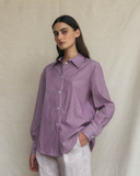 Woman wearing a plum striped shirt against a beige background
