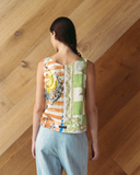Model wears spliced patchwork top against wooden background