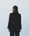 Person wearing a brown velvet suit against a light grey background