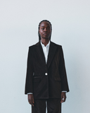 Person wearing a brown velvet suit with a white shirt against a plain background