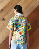 Model wearing patchwork Polo Top - mixed print shirt against a wooden wall.