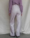 Model wearing a purple striped shirt and light pink pants against a plain background