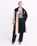 Person wearing a long, multicolored coat with a white background