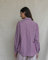 Woman wearing a plum striped shirt against a beige background