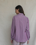 Woman wearing a plum striped shirt against a beige background