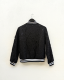 Black lace jacket with on a hanger against a white background