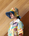 Person wearing a colorful patterned hat and shirt against a wooden background