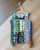 Colourful patchwork tank top on a wooden hanger against a wooden floor.