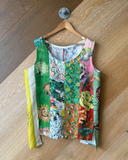 Colourful patchwork top on a wooden hanger against a wooden floor.
