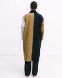 Person wearing a long, multicolored coat with a white background