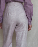 Model wearing light pink pants and a striped shirt against a plain background