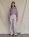 Woman wearing a plum striped shirt and high-waisted pink pants against a beige background