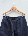 the back of a pair of denim barrel leg hanging against a white wall