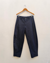 denim barrel leg pants hanging on a white wall