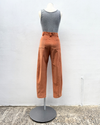 Mannequin wearing a gray tank top and brown pants against a white wall.