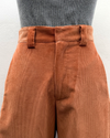Brown corduroy pants worn by a person on a light gray background