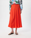 Model wearing a midi length orange skirt with patterned shirt and flip flops.