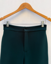 bottle green wide leg pants close up hanging on wall
