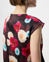 Model wearing a cowl draped top with a burgundy floral print. 