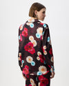 A model shown from the back wearing a burgundy shirt with a vibrant red, pink, and light blue floral print, set against a plain white studio background.