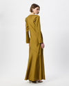A woman modeling a long-sleeved, floor-length olive yellow dress from the back, standing against a plain white studio background.