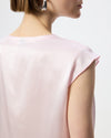 Close-up back view of a model wearing a light pink short-sleeve top against a plain white background.