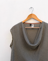 Checked Cowl Draped Top hanging against white wall.