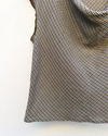 Checked Cowl Draped Top hanging against white wall.