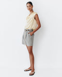 Woman wearing a light-colored top and gray shorts on a white background