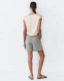 Woman wearing a light-colored top and gray shorts on a white background