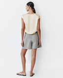 Woman wearing a beige top and gray shorts on a white background